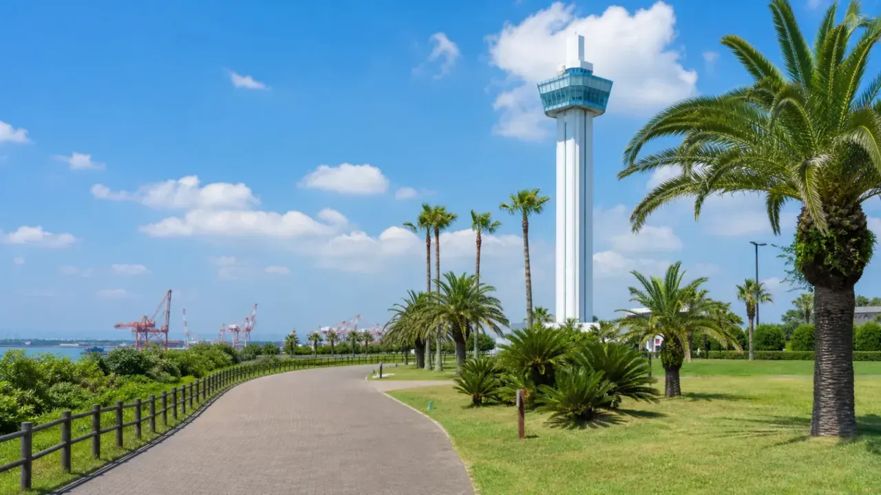 神栖市の港公園で、ヤシの木のある園路と展望塔、遠くの鹿島港を眺める晴れた日のイメージ