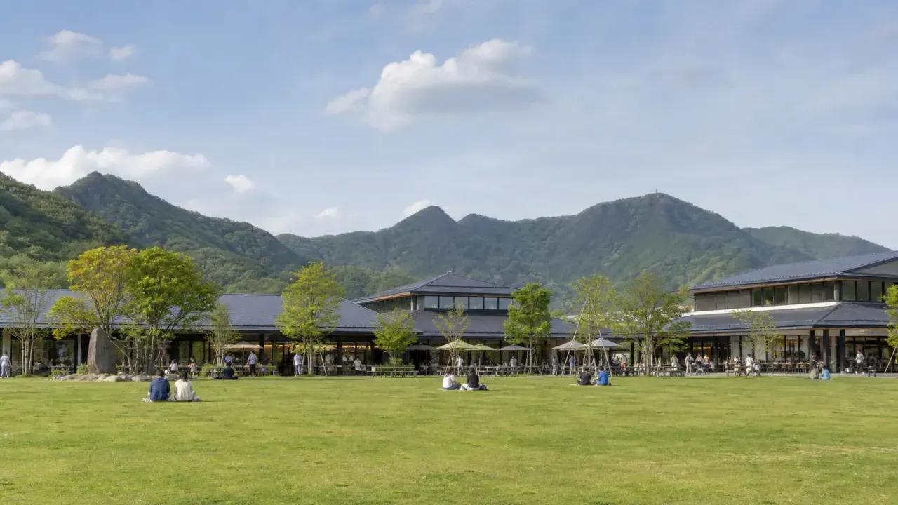 赤城山麓の道の駅を思わせる芝生広場、買い物棟、遠くの山並みを重ねたカバー画像