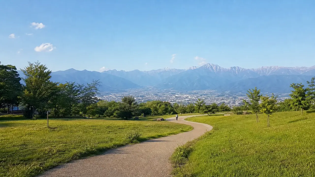 松本市アルプス公園を思わせる丘陵の園路と芝生、遠くの山並みを写した架空のカバー画像