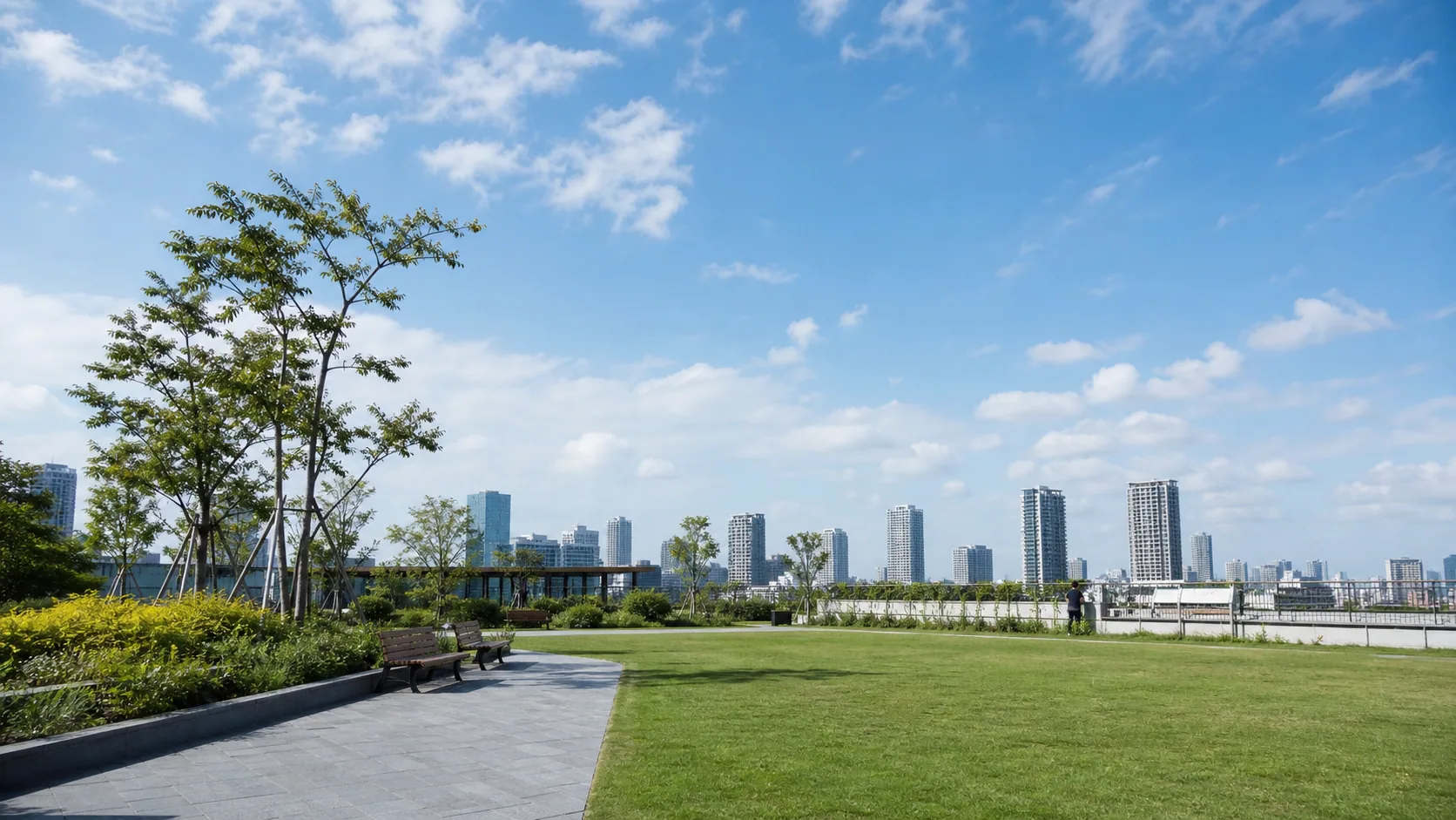 広い空と芝生がある都市公園のイメージ