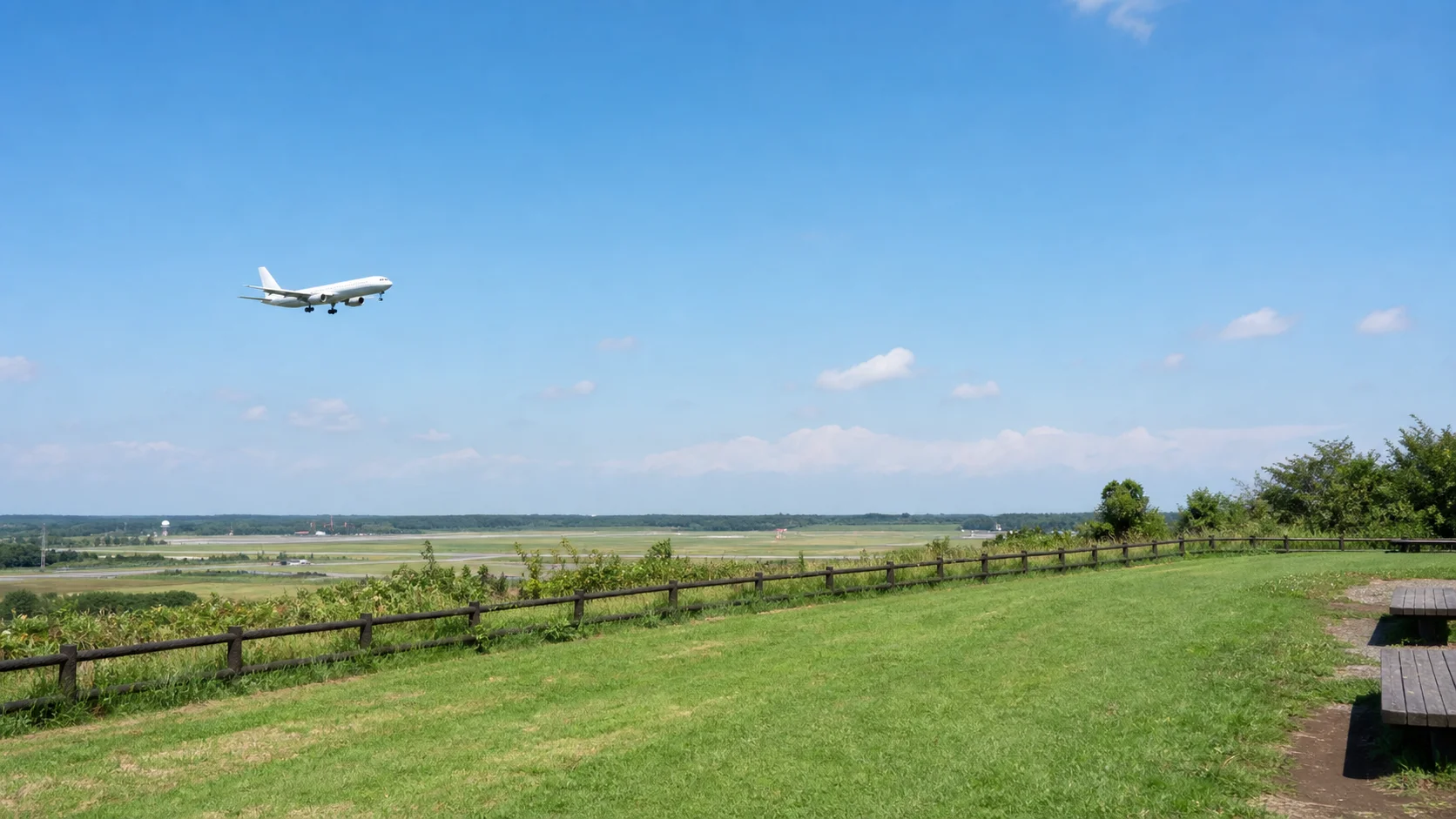 芝生の展望広場から飛行機と広い空を眺めるイメージ