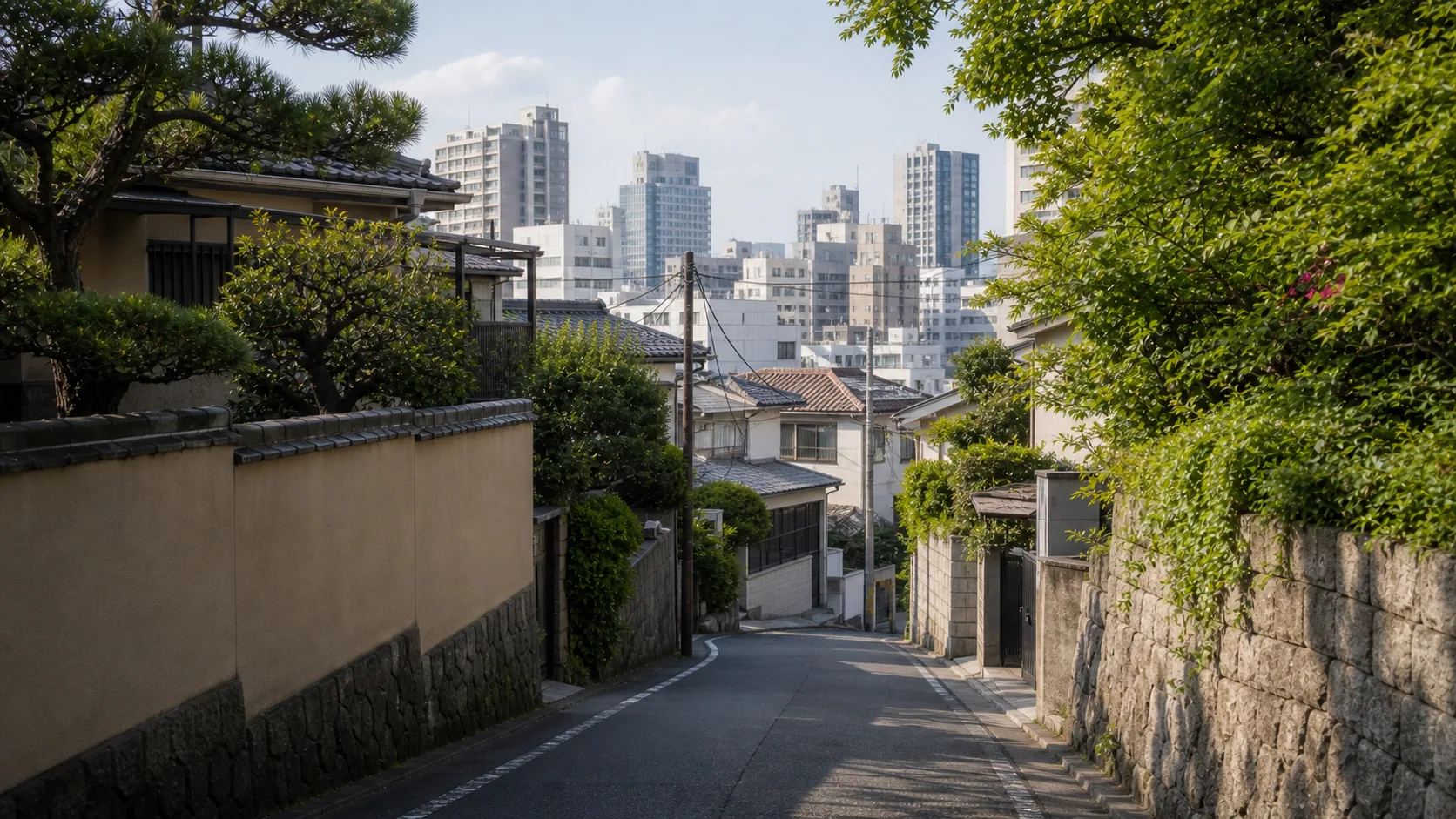 古い住宅地と新しい街並みが重なる坂道のイメージ