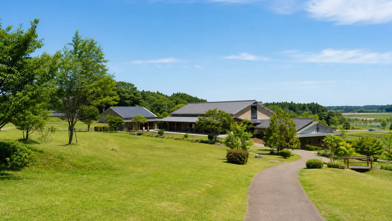 八千代グリーンビレッジを思わせる芝生広場と低い建物、田園の緑が広がる散歩イメージ